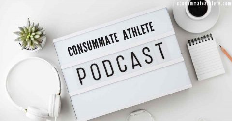A lightbox sign on a white desk displays the text "CONSÜMMATE ATHLETE PODCAST." Surrounding it are a potted succulent plant, a pair of white headphones, a coffee cup on a saucer, a notebook with a pen, and a website URL "consummateathlete.com" in the corner.
