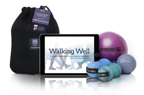 A fitness starter kit includes a mesh bag, a tablet displaying "Walking Well," a purple exercise ball, a gray exercise ball, two smaller blue balls in netting, and an instructional tag attached to the bag.