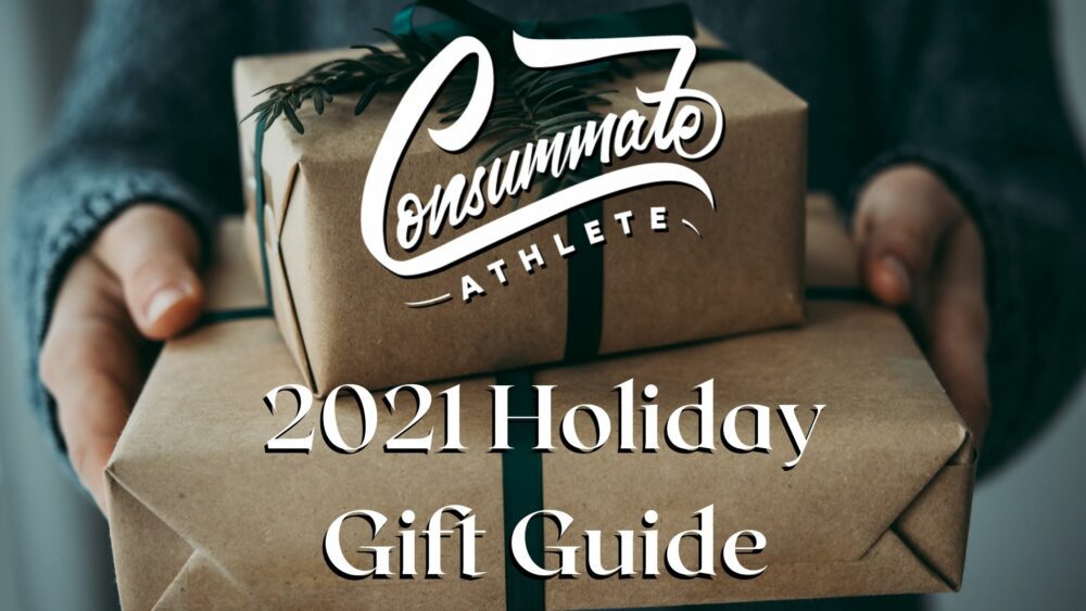 Two hands holding two neatly wrapped brown paper packages with green ribbon, accompanied by text that reads "Consummate Athlete 2021 Holiday Gift Guide.