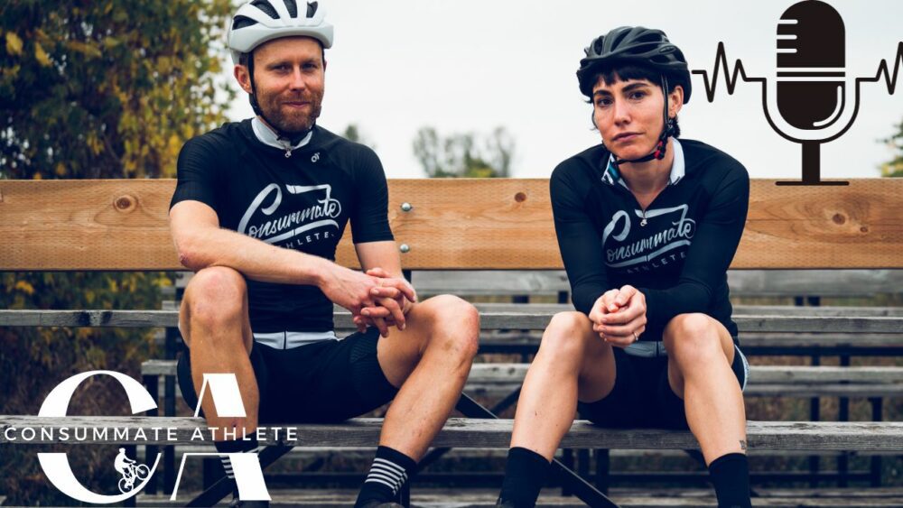 Two cyclists wearing black and white team jerseys are sitting on a wooden bench. both are looking at the camera, with a microphone icon and the logo "consummate athlete" displayed in the foreground.