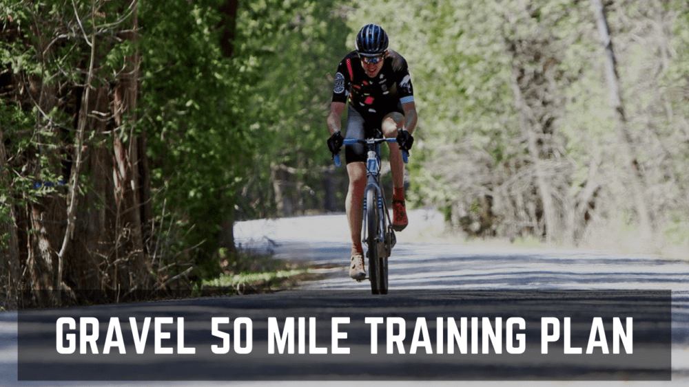 A cyclist in black and red gear rides a blue bicycle on a sunlit gravel road surrounded by lush green trees, with text overlay reading "GRAVEL 50 MILE TRAINING PLAN".