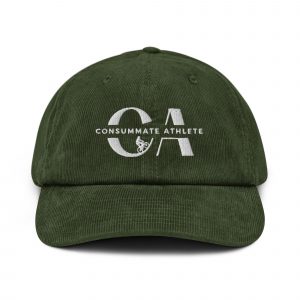A dark green corduroy baseball cap with "Consummate Athlete" embroidered on the front in white. The design features the letters "C" and "A" with a small graphic of a bicycle between them. The cap has a curved brim and six panels.