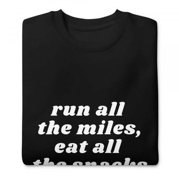 A neatly folded black sweatshirt with white text that reads, "run all the miles, eat all the snacks." The sweatshirt is displayed on a plain white background.