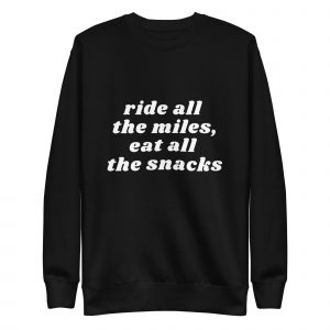 A black crewneck sweatshirt with white text that reads, "ride all the miles, eat all the snacks.